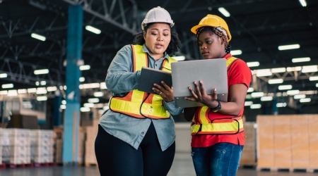 African female manager working with digital tablet checking stock with colleague worker at the warehouse factory.