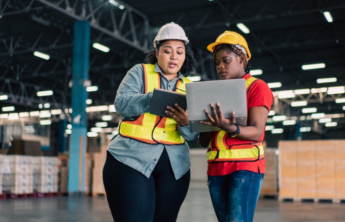 African female manager working with digital tablet checking stock with colleague worker at the warehouse factory.